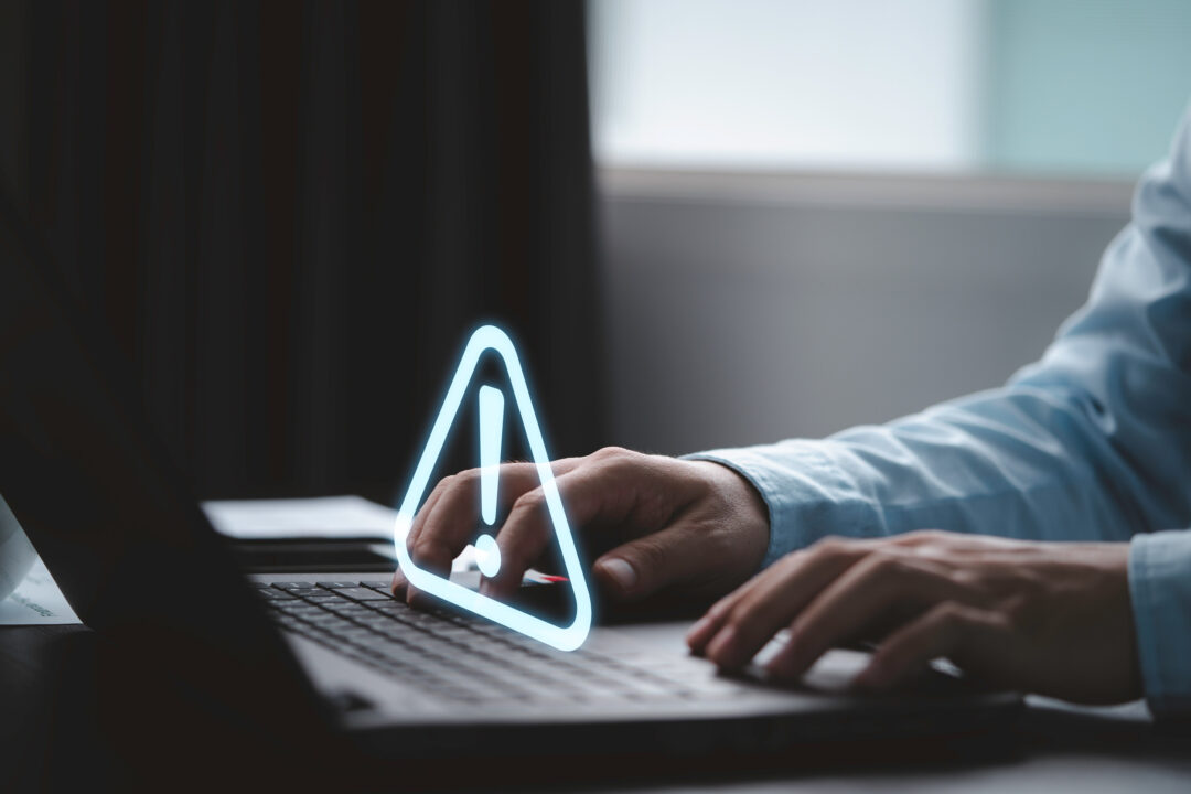 Businessman using computer laptop with triangle caution warning